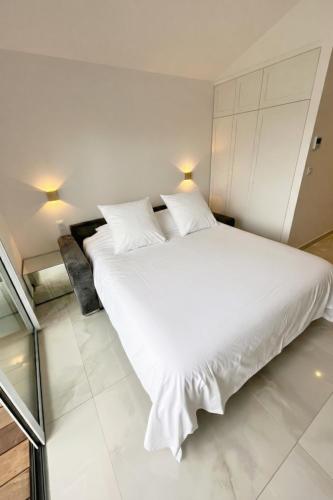 a bedroom with a large white bed with two pillows at EHDΞN Biarritz Arbonne in Arbonne