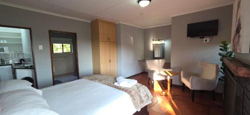 a bedroom with a bed and a kitchen and a television at Boabab at Greenway Woods in White River