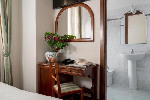 a bedroom with a desk with a sink and a mirror at Hotel Boccaccio in Florence