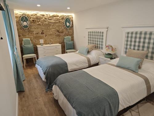 a bedroom with three beds and a stone wall at Arturana turismo in Ollauri