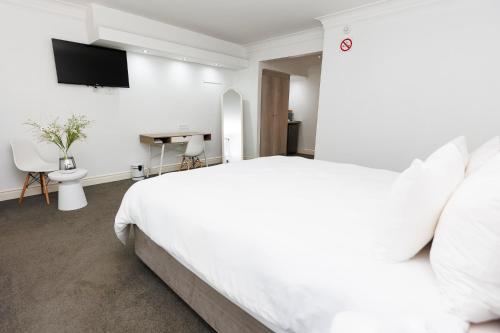 a white bedroom with a white bed and a tv at 5-Min Walk to CTICC - Central & Cosy Hotel Stay in Cape Town
