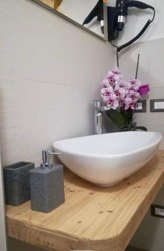 a bathroom with a white sink and flowers on a wooden counter at B&B Ciesa la Vèrda in Rocca Pietore