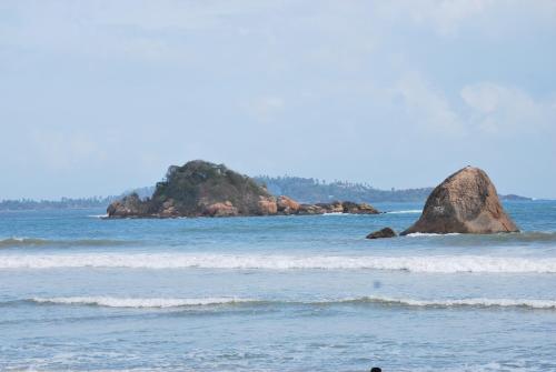 a person standing in the water at the beach at ilamparuma Hotel in Weligama
