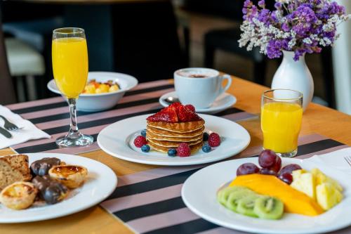 a table topped with plates of breakfast foods and orange juice at HF Ipanema Park in Porto