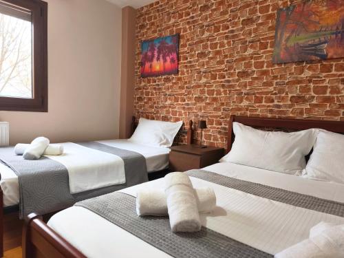 a bedroom with two beds and a brick wall at Country House on Mount Olympus in Kariá
