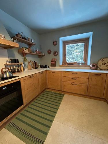 eine Küche mit Holzschränken, einem Fenster und einem Teppich in der Unterkunft Chalet Angelo in Ponte di Legno