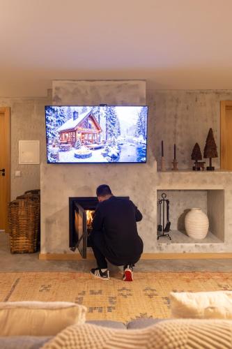 a man kneeling in front of a fireplace in a living room at Exclusive Pena Rio in Ribeira de Pena