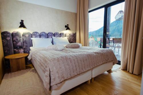 a bedroom with a large bed and a balcony at Ґонт - затишний будинок з чаном біля Буковелю in Tatariv