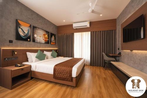 a hotel room with a bed and a desk at Nilayat Inn in Ollūr