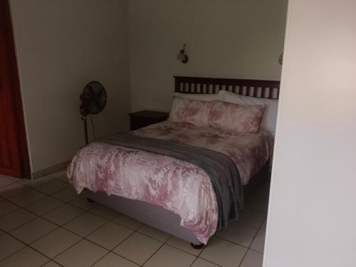 a bedroom with a bed with pink sheets and a fan at Eagles Lodge One in Vosburg