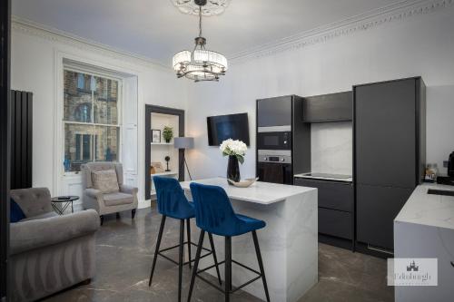 a kitchen with a white counter and blue bar stools at 2Bedroom apartment by the castle in Edinburgh