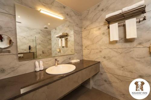 a bathroom with a sink and a mirror at Nilayat Inn in Ollūr