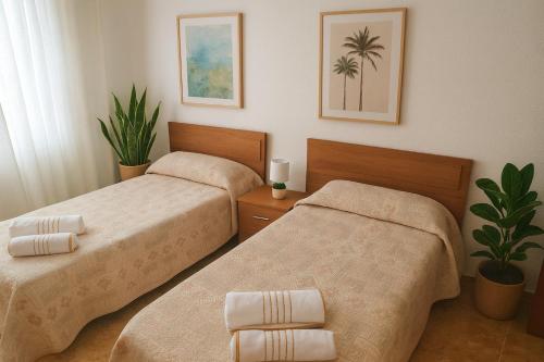 two beds in a hotel room with palm trees at Pensión El Chalet in Torrejoncillo del Rey