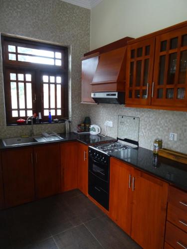 a kitchen with wooden cabinets and a black stove top oven at Ok Cabana Negombo in Negombo