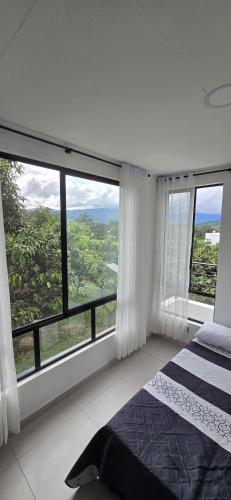 a white bedroom with large windows and a bed at El Ensueño - Rest House in La Mesa