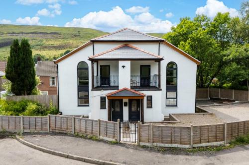 a white house with a fence in front of it at The Old Band Room House No 1 in Blaina