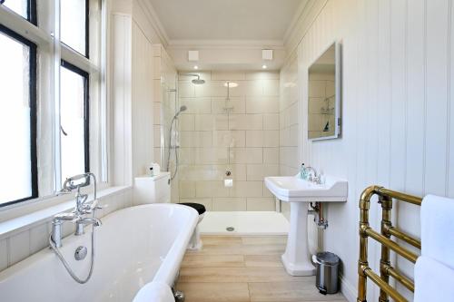 ein weißes Badezimmer mit Badewanne und Waschbecken in der Unterkunft Stanton Manor Hotel in Chippenham