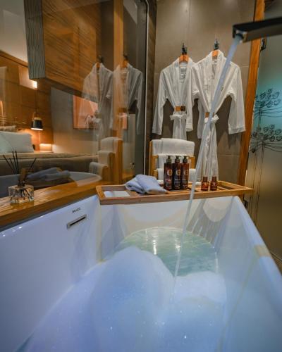 a bathroom with a bath tub with clothes on hangers at Wood Hotel in Gramado
