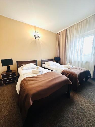 two beds in a hotel room with a window at Rezydencja Rosato in Mirkow
