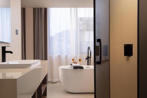 a bathroom with a tub and a sink at Fenghuang Story Hotel in Fenghuang County