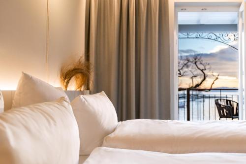 a bed with white pillows in front of a window at Hafenhotel zu Putbus in Putbus