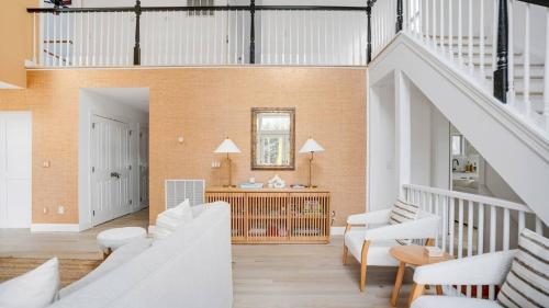 a living room with white furniture and a staircase at Villa Willow & Waves in East Hampton