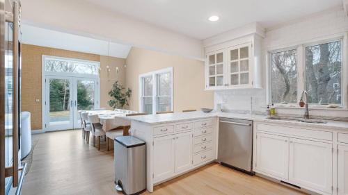 a kitchen with white cabinets and a dining table at Villa Willow & Waves in East Hampton