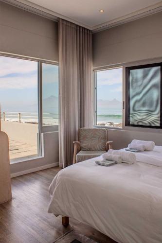 a bedroom with a bed and a view of the beach at Bokkombaai in Bloubergstrand