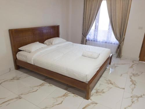 a bedroom with a bed with white sheets and a window at Jenny's Villa and Restaurant in Tuktuk Siadong