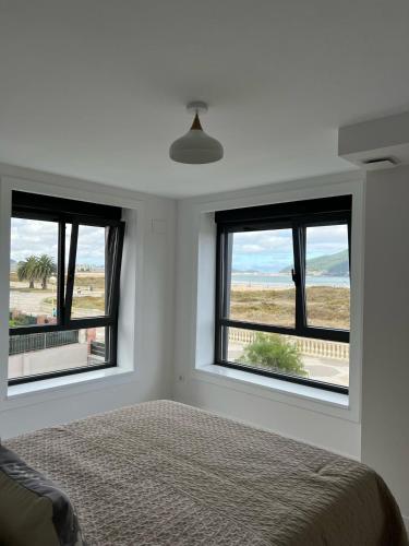 a bedroom with three windows and a bed with a view at Lujosa casa en primera línea playa increibles vistas mar in Laredo