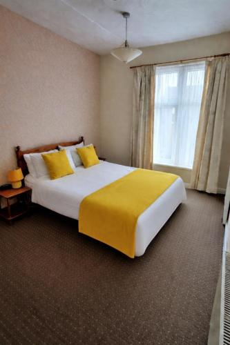 a bedroom with a large bed with yellow sheets and a window at Sunset Suites in Blackpool