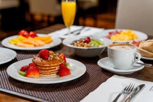 a table with pancakes and fruit and a cup of coffee at HF Ipanema Porto in Porto