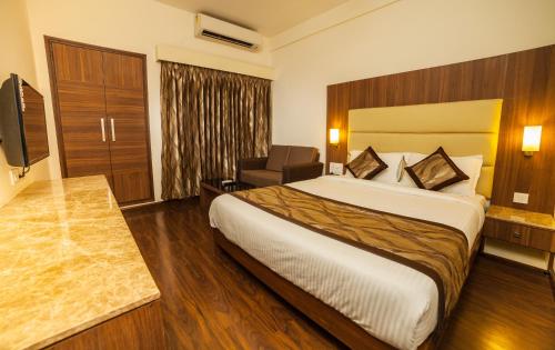a hotel room with a bed and a chair at Hotel Vales Park in Dindigul
