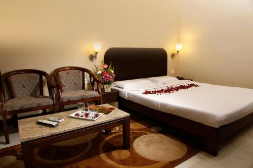 a bedroom with a bed and two chairs and a table at Hotel Vales Park in Dindigul