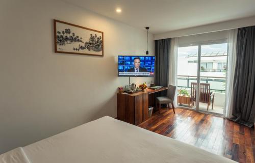 a hotel room with a bed and a desk and a television at Somadevi Residence in Siem Reap