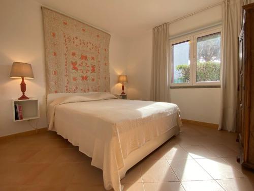 a bedroom with a white bed and a window at Casa Manacá Vilamoura in Quarteira