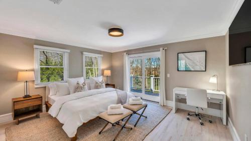 a bedroom with a bed and a desk and windows at Villa Saltwater Haven in East Hampton
