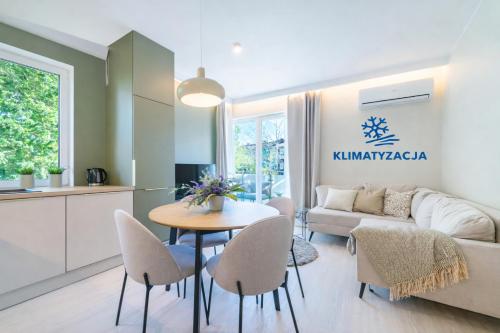 a kitchen and a living room with a table and chairs at Unique View Apartment - 3pok, 4 łóżka, widok na rzekę, centrum, Netflix, parking, winda in Iława