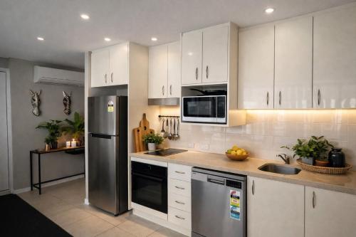 a kitchen with white cabinets and a stainless steel refrigerator at Brighton Shores 1 bedroom apartment in Gold Coast