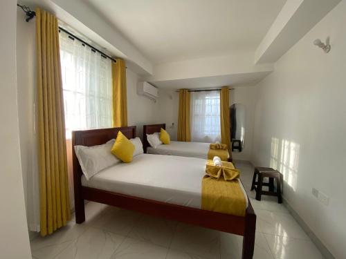a bedroom with two beds with yellow curtains at Leah's Luxury Villa in Mombasa