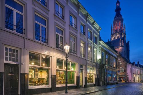 a street with buildings and a clock tower at night at Sutor Hotel in Breda