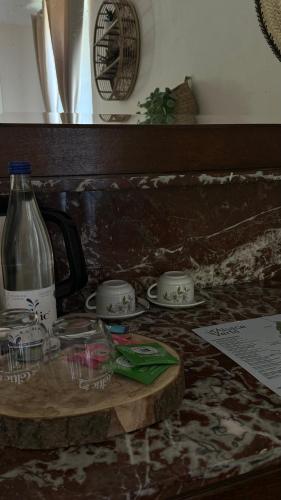a table with cups and plates and a bottle on it at Ferme Mellon in Niederbronn-les-Bains