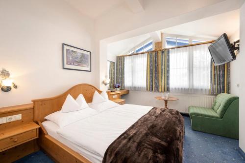 a hotel room with a bed and a green chair at Sporthotel Snowwhite in Obertauern