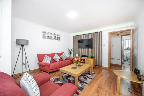 a living room with a red couch and a table at Super Prime Train Station Inverkeithing by TBA in Inverkeithing