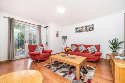 a living room with two red couches and a table at Super Prime Train Station Inverkeithing by TBA in Inverkeithing