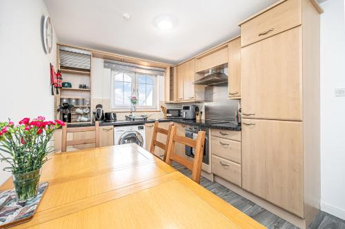 a kitchen with wooden cabinets and a wooden table at Super Prime Train Station Inverkeithing by TBA in Inverkeithing