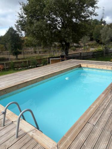 a large blue swimming pool with a wooden deck at Ohana Gerês House in Ruivãis