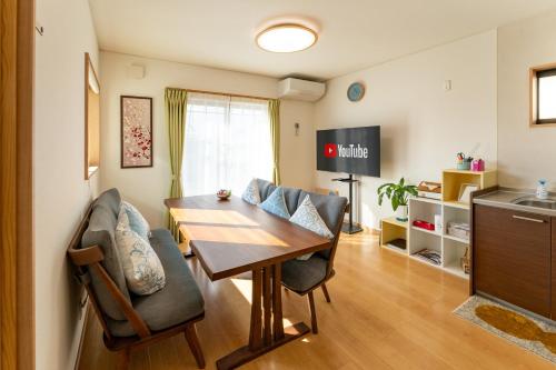 a dining room with a table and chairs and a kitchen at 貸切宿 和の音 WA no NE in Kumamoto