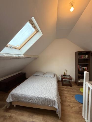 a attic bedroom with a bed and a window at Duplex proche aéroport CDG et Paris in Sarcelles