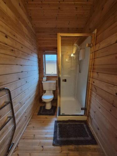 a wooden bathroom with a toilet and a shower at Eas Lodge in Tobermory